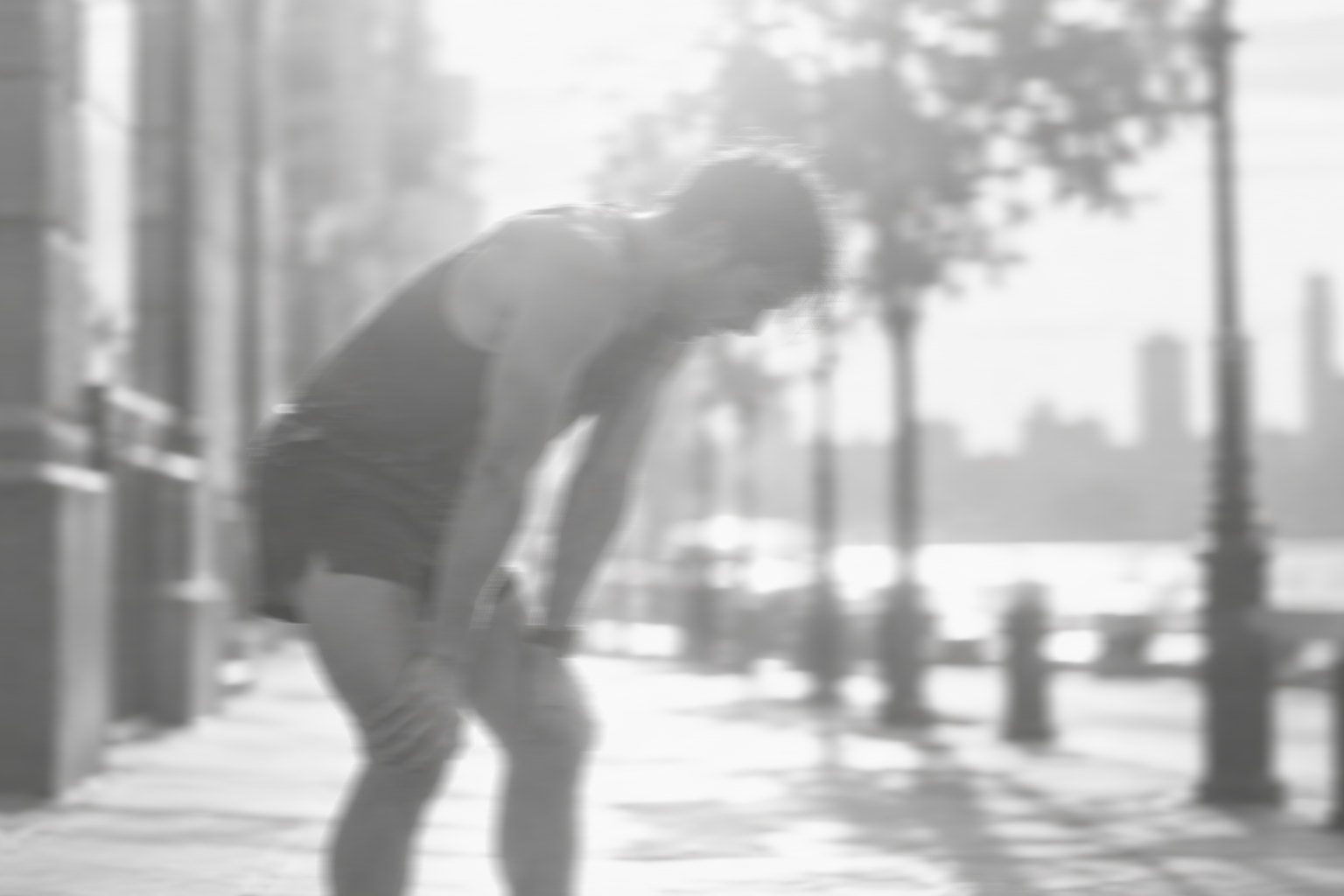 Runner catching their breath after a city run in a black-and-white photograph.